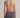 Person wearing a pink halter top with open back and gray jeans on a neutral background