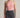 Person wearing a pink halter top and black jeans against a neutral background