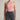 Person wearing a pink halter top and black jeans against a neutral background