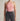 Person wearing a pink halter top and black jeans against a neutral background