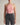 Person wearing a pink halter top and black jeans against a neutral background