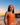 Woman in an orange swimsuit standing on a beach at sunset.