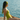 Woman in a green swimsuit sitting on a wooden dock by the water.