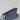 A small zippered pouch with a navy blue, white, and blue geometric pattern, resting on a light-colored wooden surface against a plain white wall.